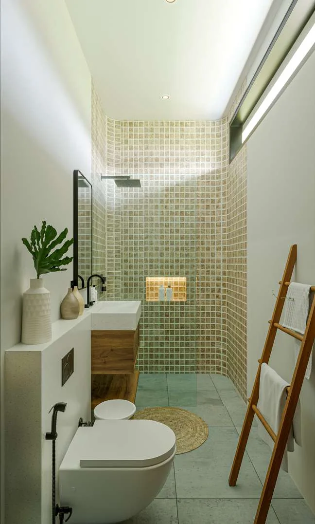 A narrow bathroom in small sage tile with a teak ladder of towels.